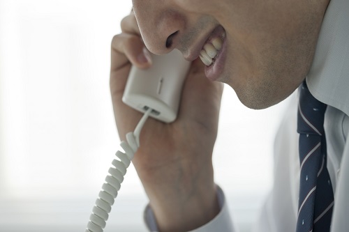 不気味な笑みを浮かべ電話をする男性